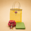 Yellow organza bag matki hamper with cotton blouse piece and Lakshmi haldi kumkum set for Varalakshmi Vratham return gifts.