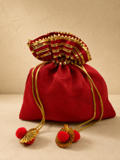 Premium red silk potli bag with decorative pleated golden border, drawstring closure, and pom-pom tassels for weddings, return gifts, festive gifting, pooja ceremonies, and jewellery packaging.