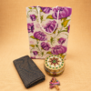 Floral paper gift bag with Meenakari decorative box, brocade blouse piece, and Lakshmi haldi kumkum set for traditional return gifts.